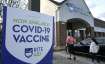 People walk past a COVID-19 vaccine sign as they enter a