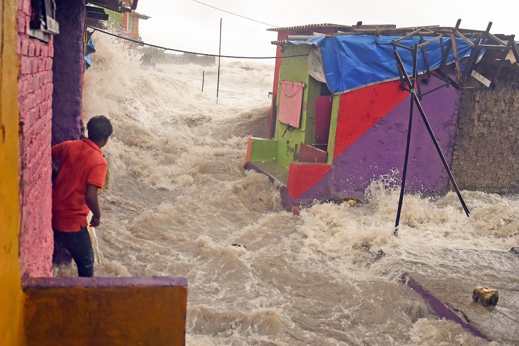 A man watches a high tide seawave as it enters the shanty town near the shore, at Bandra in Mumbai on Saturday.