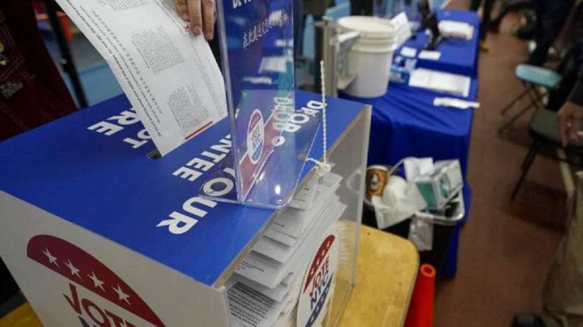 A voter drops an absentee ballot in a locked ballot box during early voting in New York.